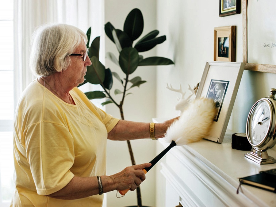 woman dusting fireplace mantle
