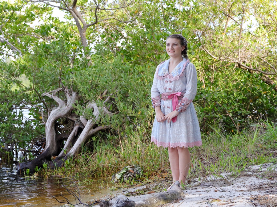 girl standing by stream in wooded area