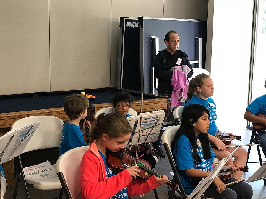 Teacher teaching young kids to play violin