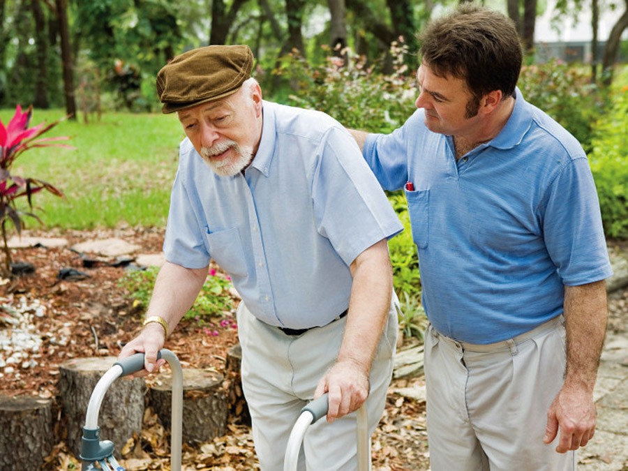 Younger man taking a walk with older gentleman with a walker
