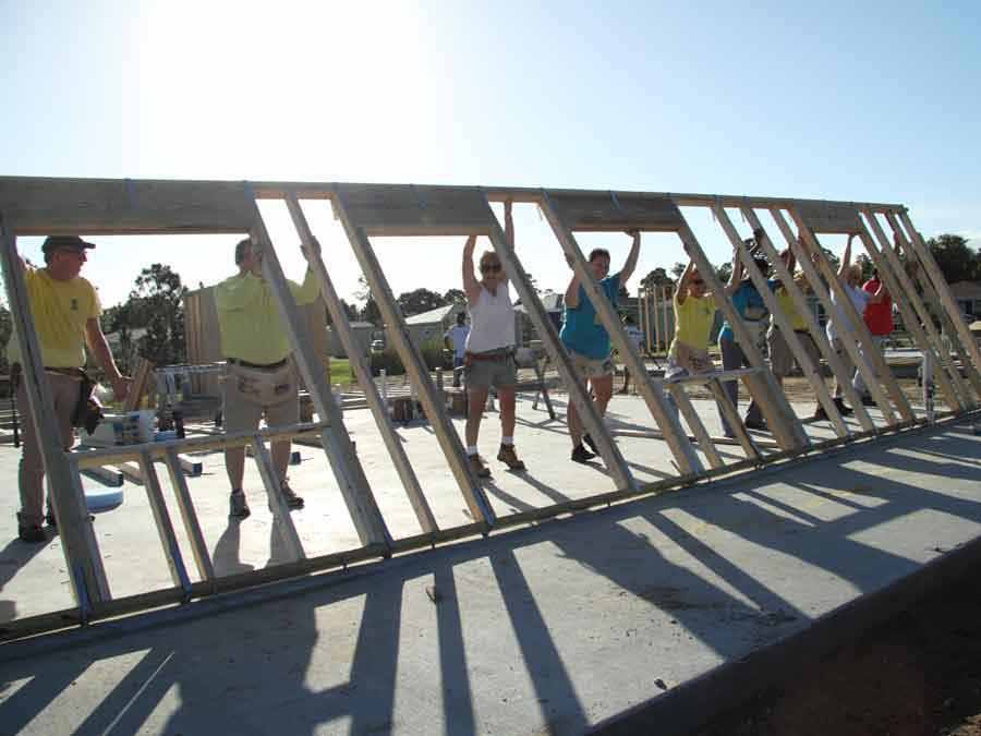 Volunteers raising wall frame for new home